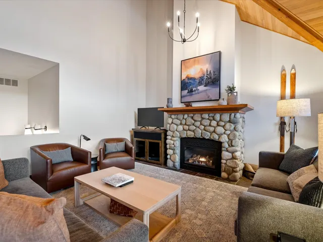 Living area with high vaulted ceiling, a fireplace, wood ceiling, beamed ceiling, and an inviting chandelier