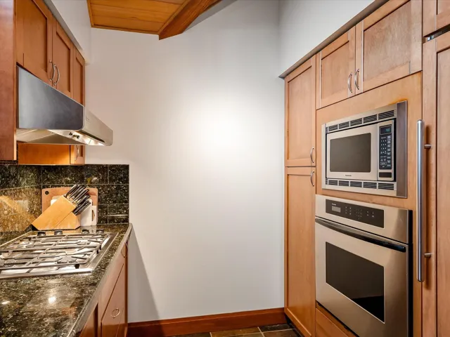 Kitchen featuring a healthy amount of sunlight, under cabinet range hood, tasteful backsplash, and stainless steel gas stovetop