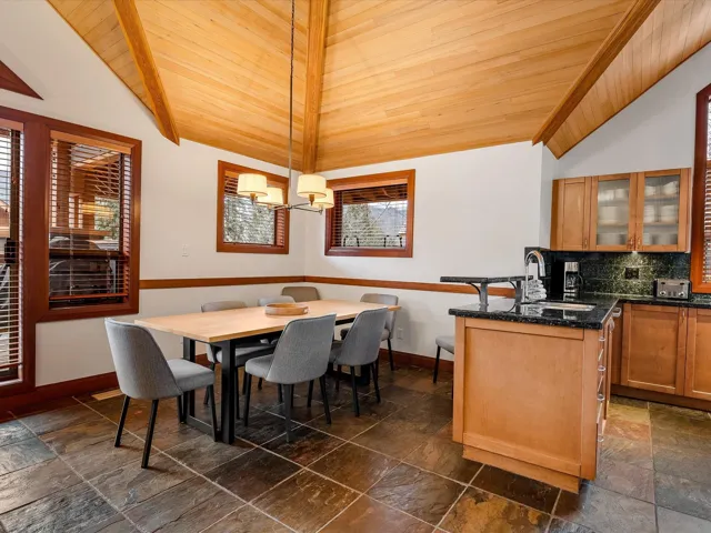 Living room featuring high vaulted ceiling, wood ceiling, stone finish floor, a chandelier, and baseboards
