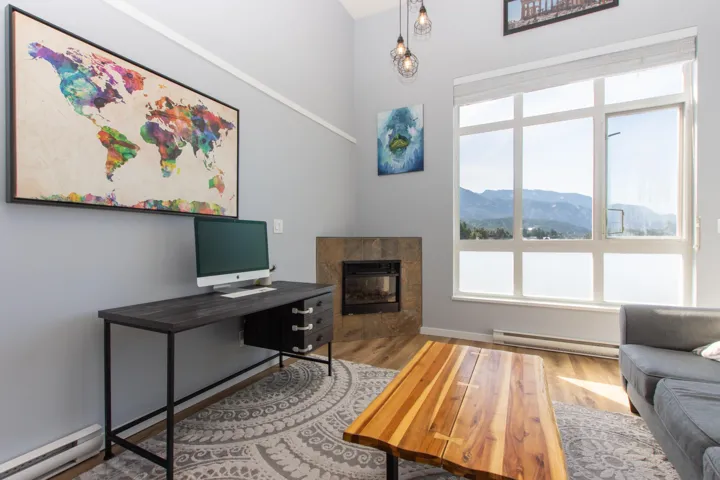 Living room with a baseboard heating unit, light wood-type flooring, and a fireplace