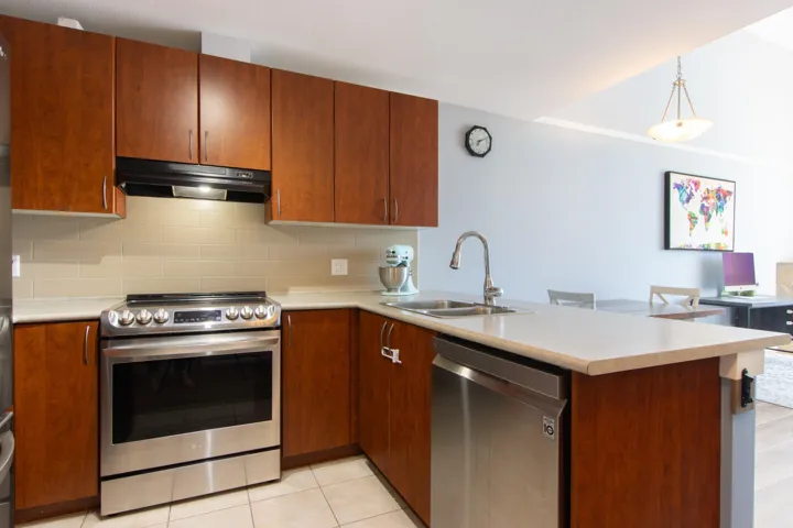 Kitchen with stainless steel appliances, light countertops, tasteful backsplash, and a peninsula