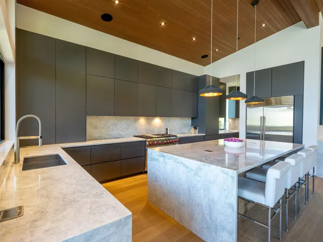 Kitchen featuring modern cabinets, light stone countertops, light wood-style floors, a breakfast bar area, and a center island