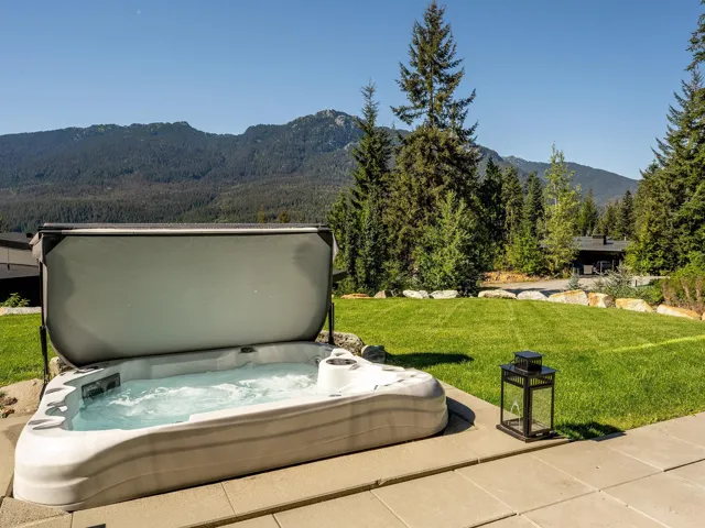 View of patio with a mountain view, a covered hot tub, and a wooded view