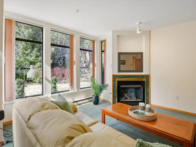 Living room featuring baseboards, a glass covered fireplace, and carpet