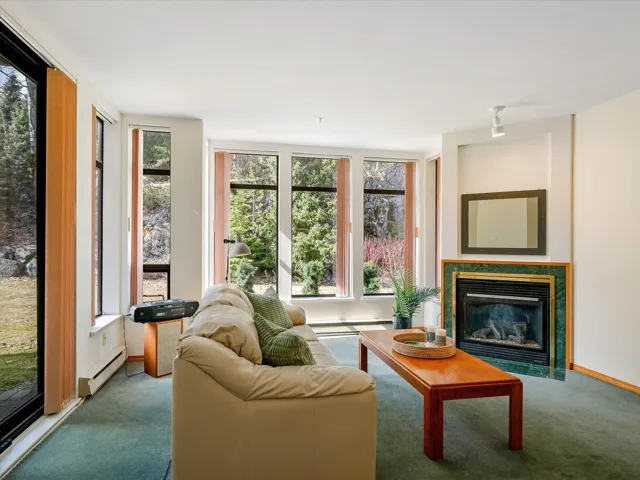 Carpeted living area with a fireplace with flush hearth, baseboards, a baseboard heating unit, and a baseboard radiator