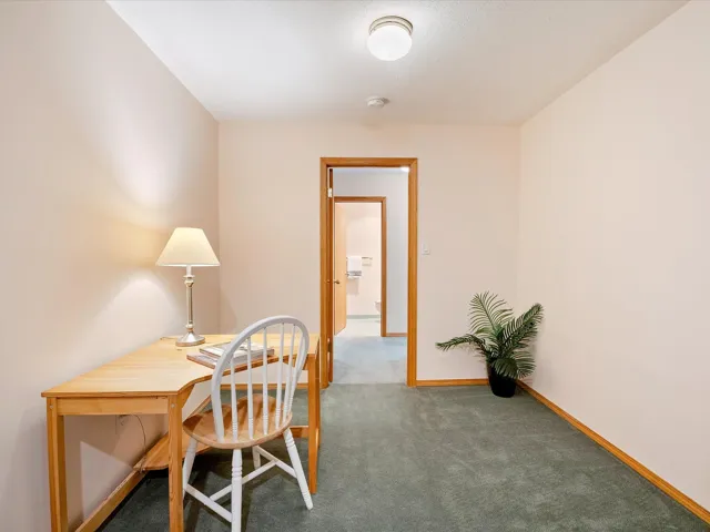 Carpeted home office featuring baseboards