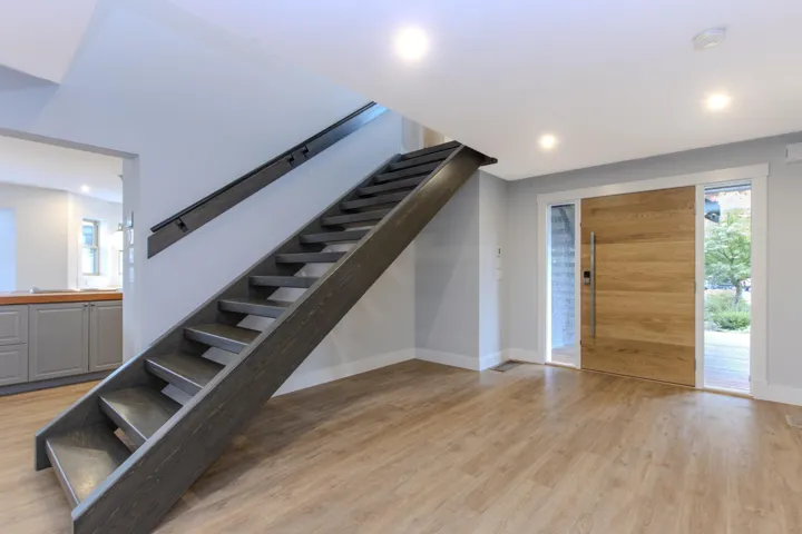 Stairway with healthy amount of natural light, wood finished floors, and recessed lighting