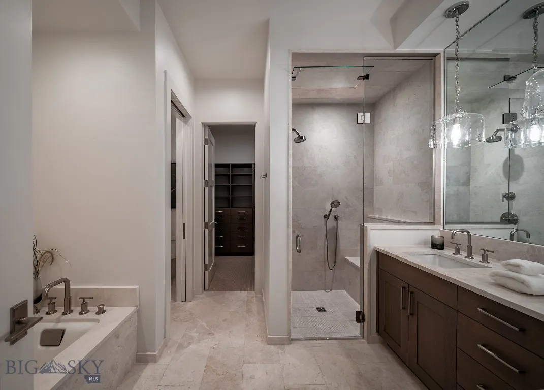 Primary bath with dual vanity, walk-in closet, walk-in shower, and tub.