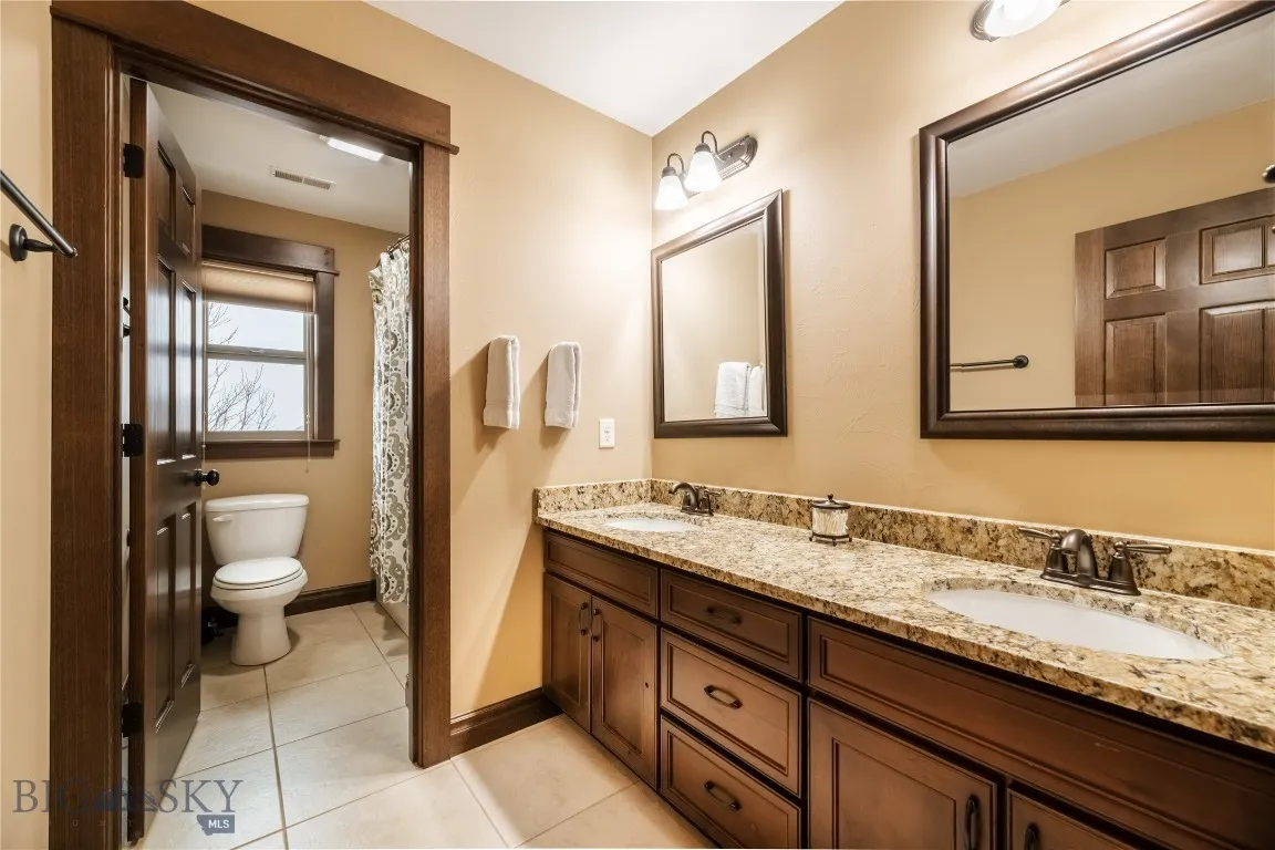 Second floor full bath with dual vanity, wood cabinetry and granite countertop, separate water closet and shower/tub combo.