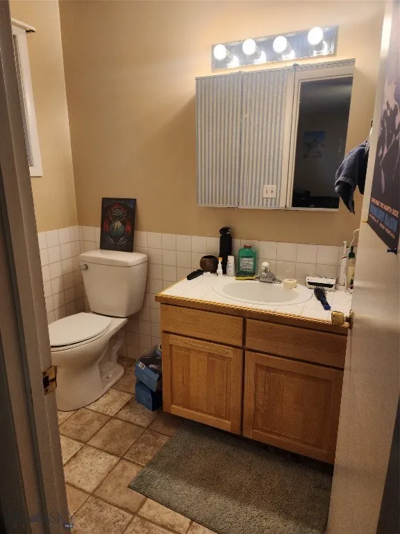Bathroom with toilet, vanity, and tile walls