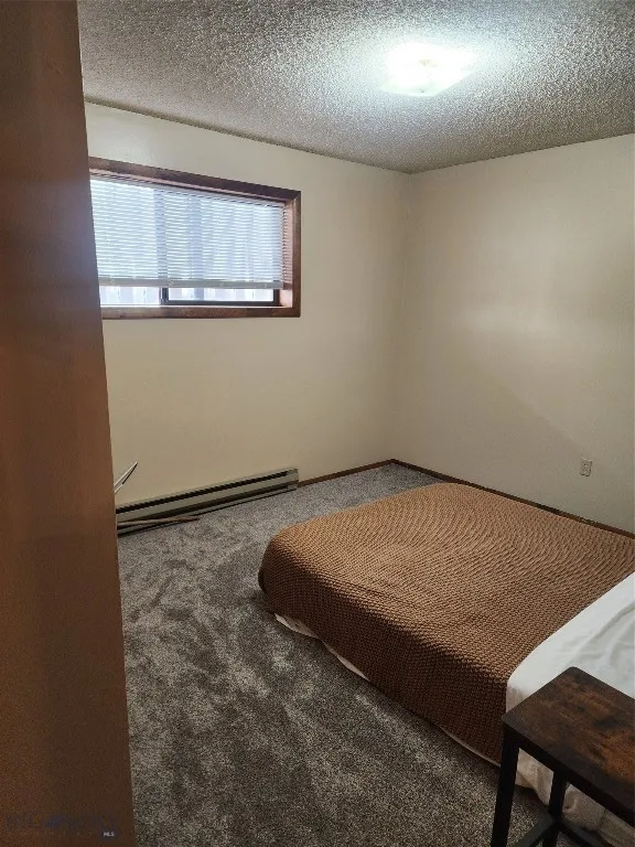 Unfurnished bedroom with a baseboard radiator, a textured ceiling, and carpet floors