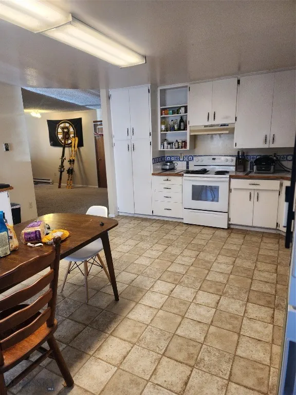 Kitchen with white cabinets, stove, and ventilation hood