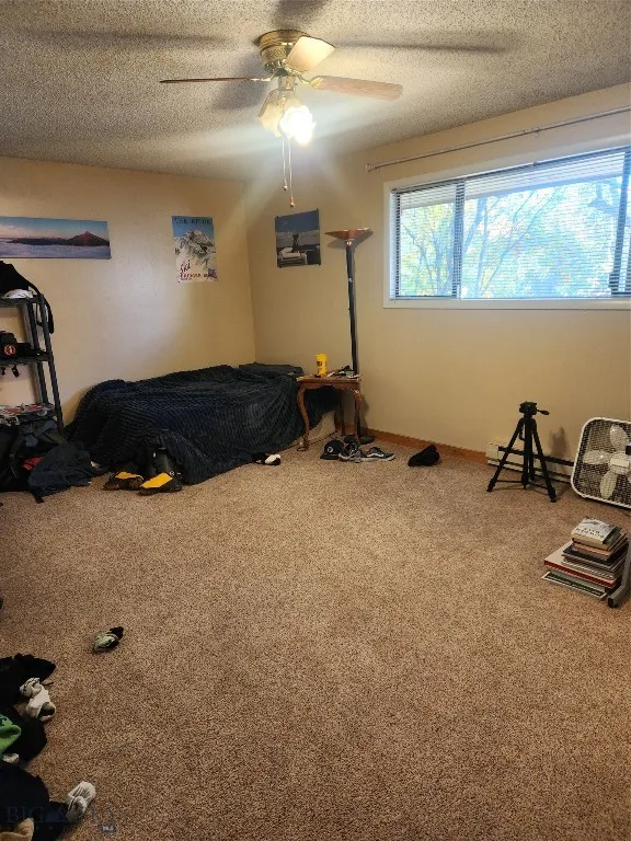 Bedroom featuring ceiling fan, a textured ceiling, carpet flooring, and baseboard heating