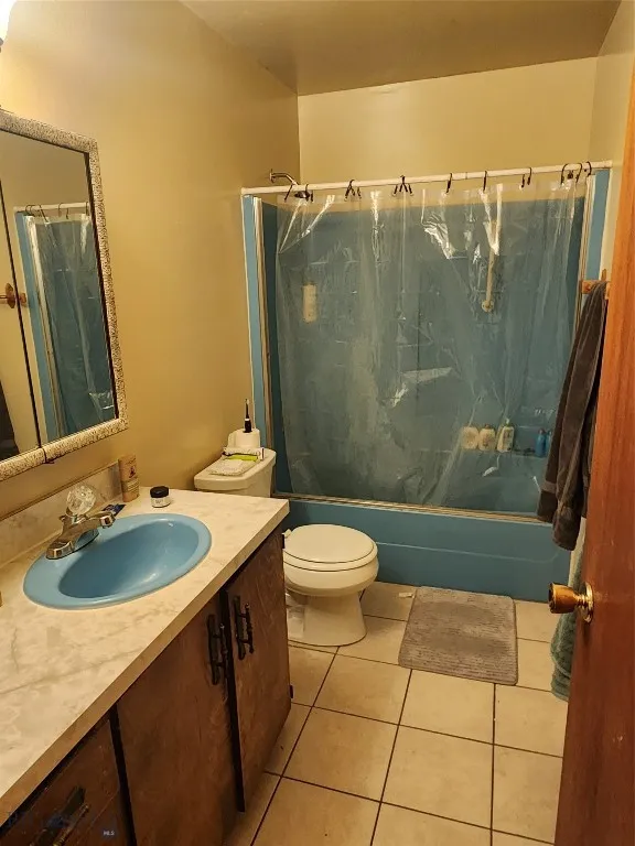 Full bathroom featuring tile patterned flooring, vanity, toilet, and shower / tub combo with curtain
