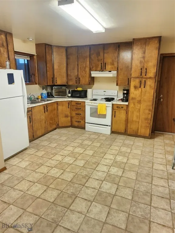 Kitchen with white appliances, extractor fan, and sink