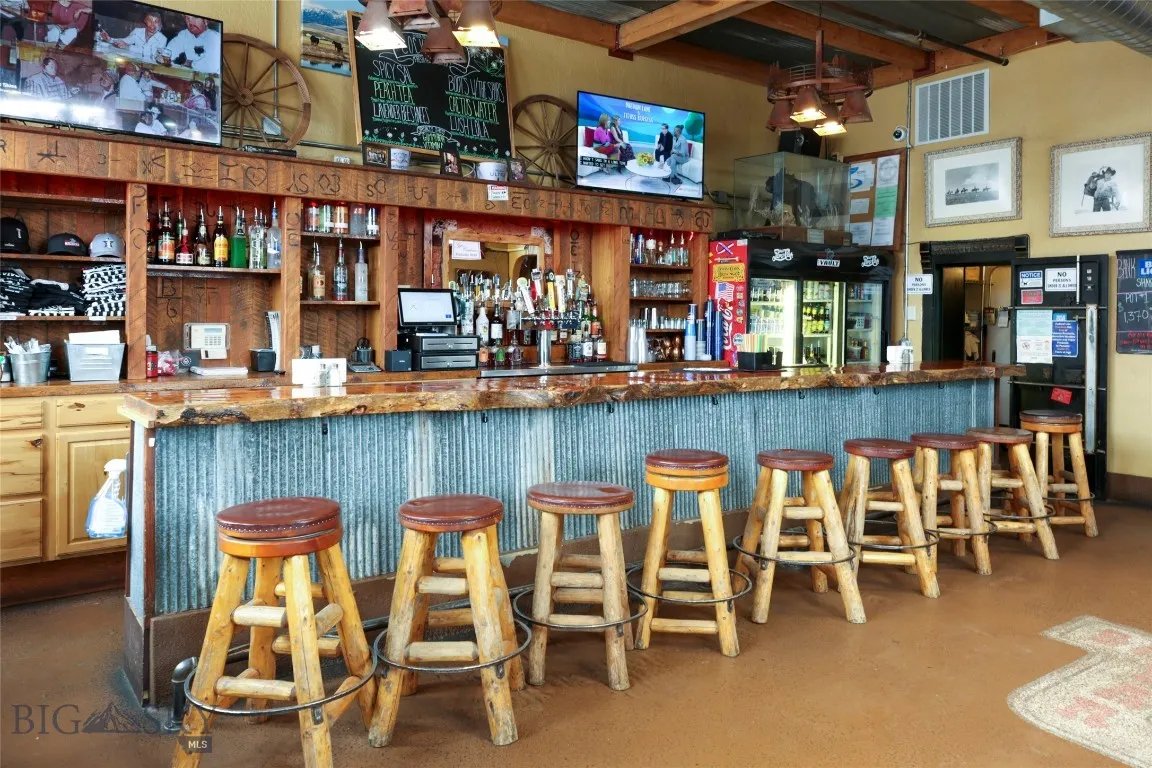 Bar featuring beamed ceiling, decorative light fixtures, concrete flooring, and light brown cabinetry