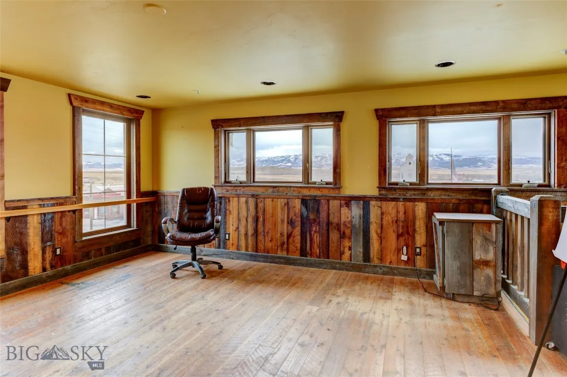 Living area or office with a mountain view, light hardwood / wood-style floors, and wooden walls