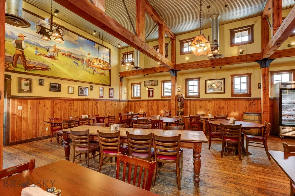 Dining room with beam ceiling, hardwood / wood-style floors, a healthy amount of sunlight, and a high ceiling
