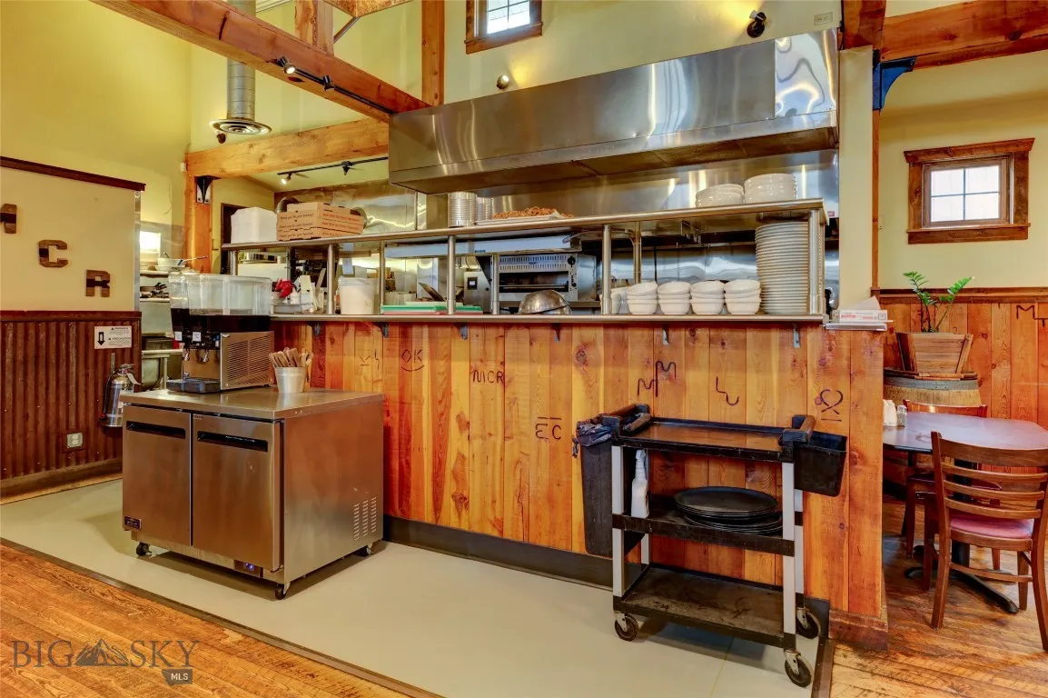 Kitchen with range hood, wood walls, light wood-type flooring, and a high ceiling