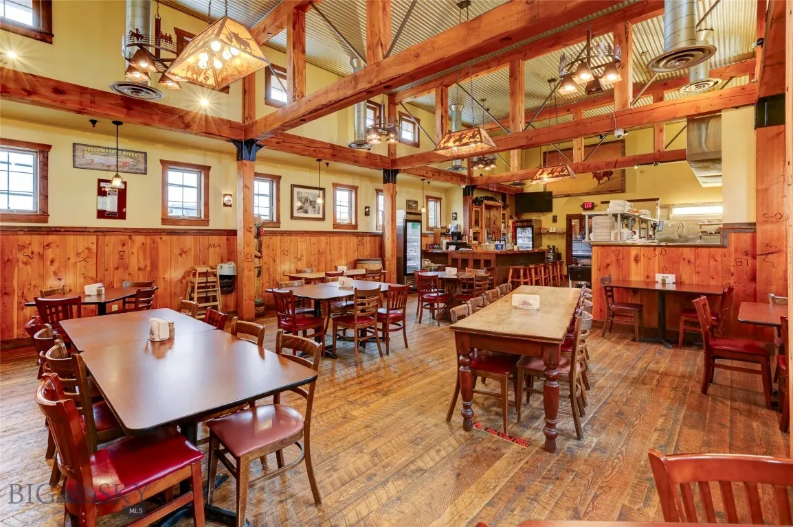 Dining room featuring hardwood / wood-style flooring, beam ceiling, wood walls, and high vaulted ceiling