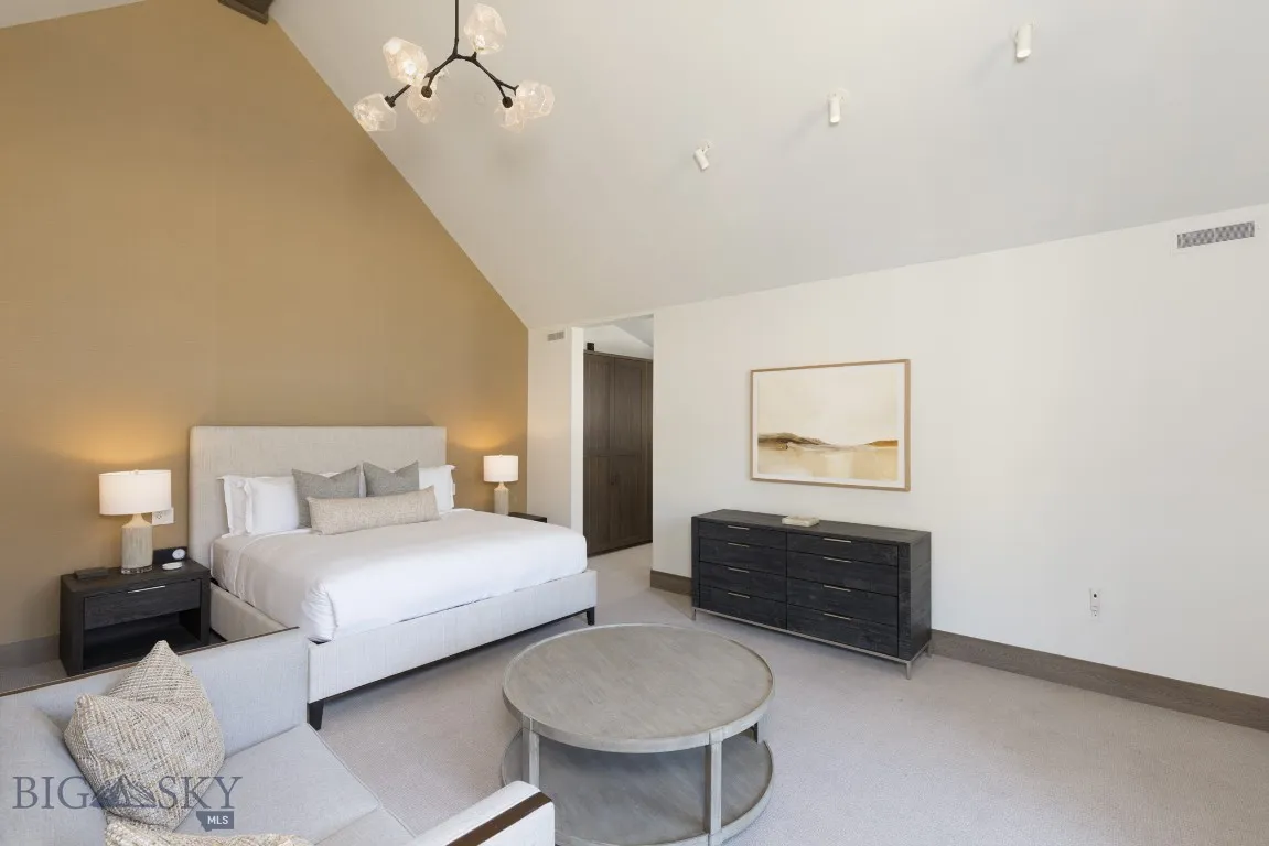 Bedroom featuring light colored carpet, high vaulted ceiling, and an inviting chandelier