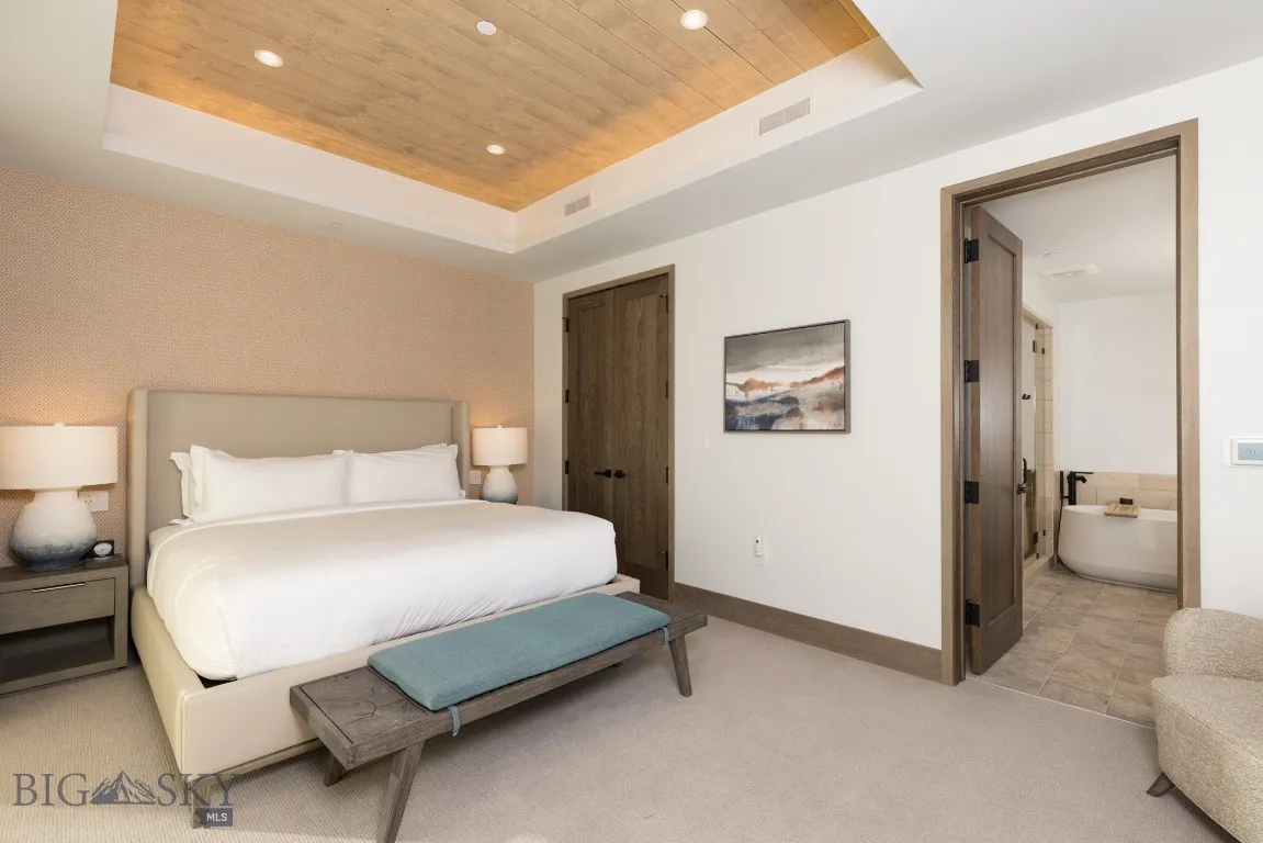 Bedroom with a raised ceiling, light carpet, a closet, and wood ceiling
