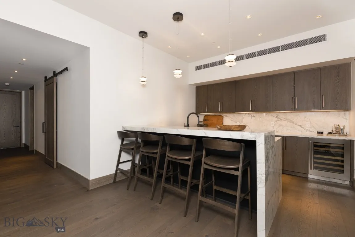 Bar featuring backsplash, hanging light fixtures, wine cooler, dark hardwood / wood-style floors, and a barn door