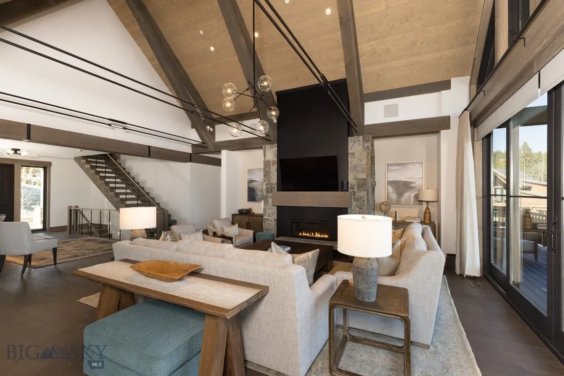 Living room featuring dark wood-type flooring, high vaulted ceiling, beamed ceiling, a fireplace, and wood ceiling