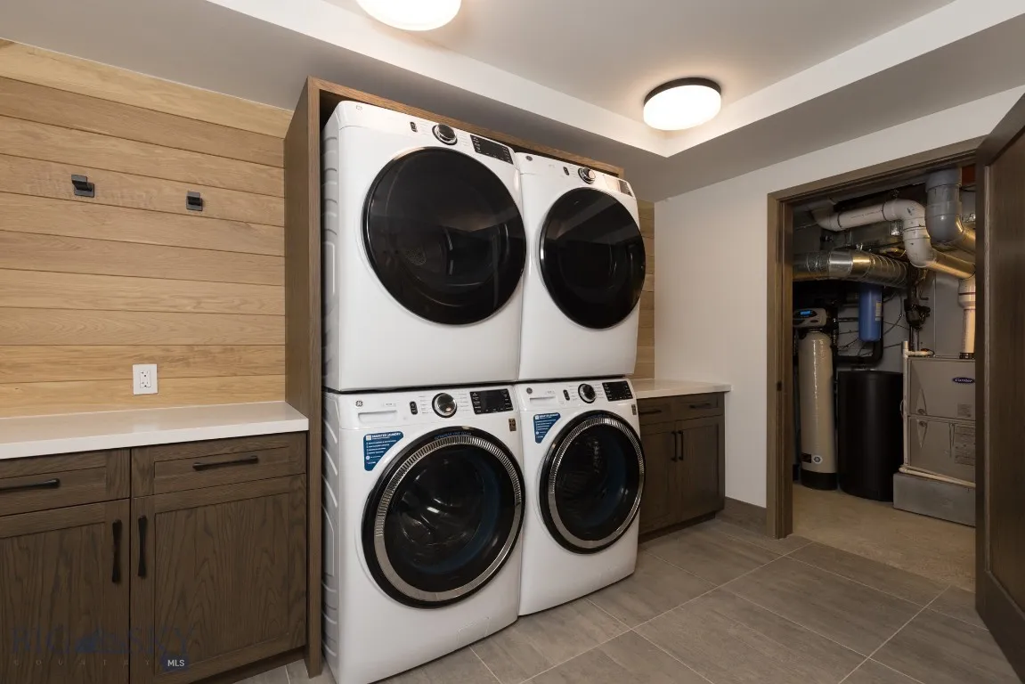 Laundry area with cabinets, light tile patterned floors, washer and clothes dryer, and stacked washer / drying machine