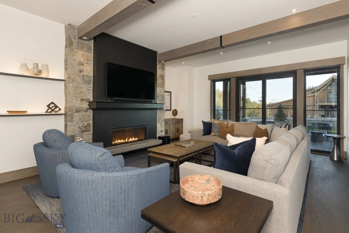Living room with beamed ceiling, a large fireplace, and dark hardwood / wood-style flooring