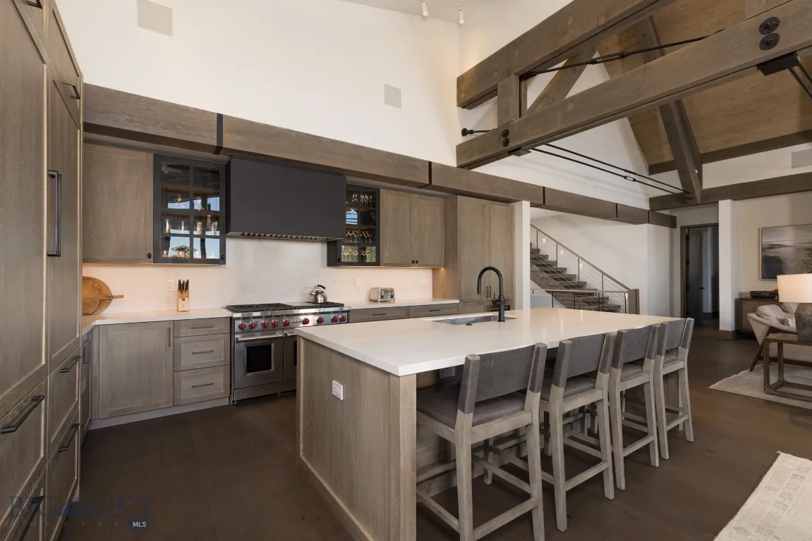 Kitchen with sink, dark wood-type flooring, range with two ovens, a kitchen bar, and a kitchen island with sink