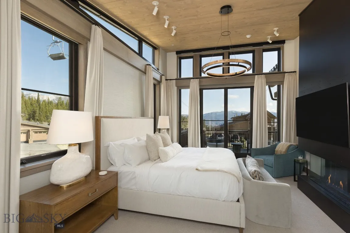 Bedroom featuring a towering ceiling, track lighting, an inviting chandelier, and wooden ceiling