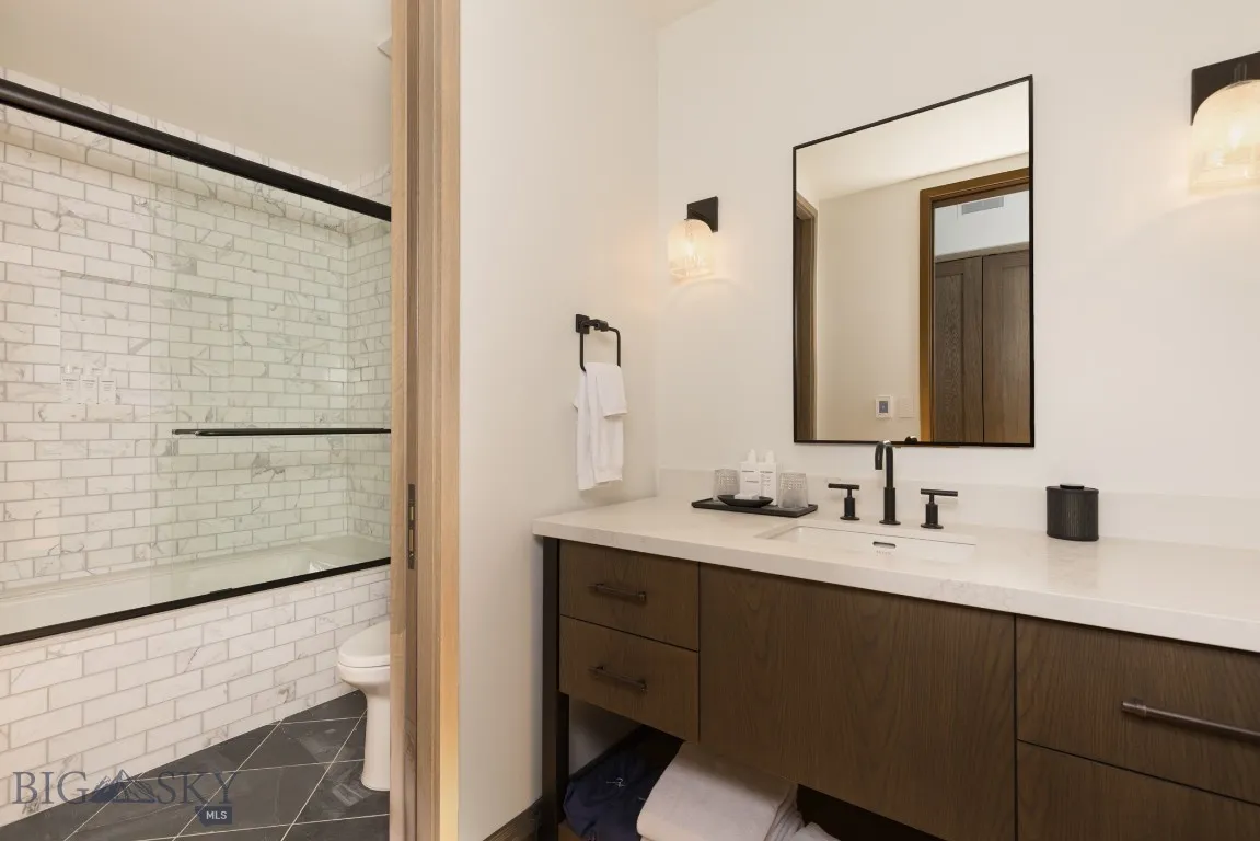 Full bathroom with tile patterned flooring, vanity, combined bath / shower with glass door, and toilet
