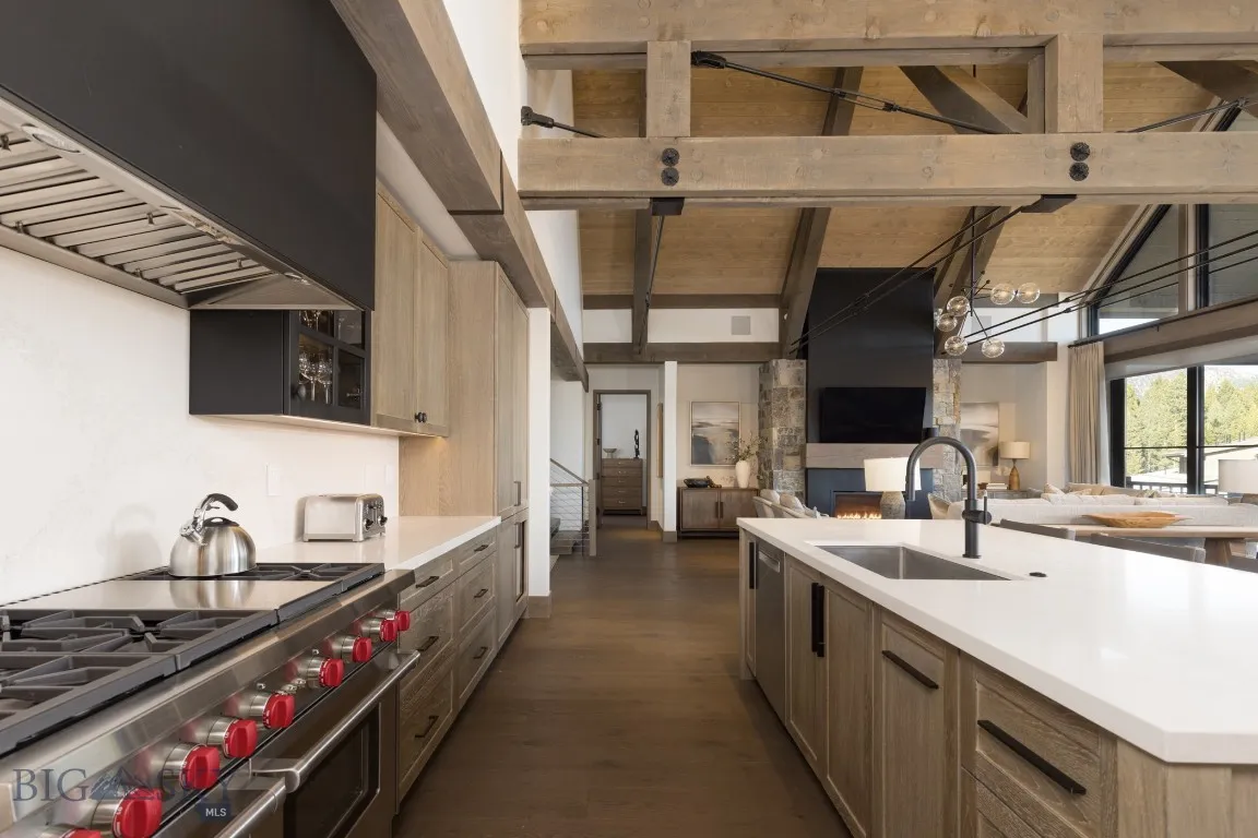 Kitchen with premium range hood, stainless steel appliances, dark wood-type flooring, sink, and lofted ceiling with beams