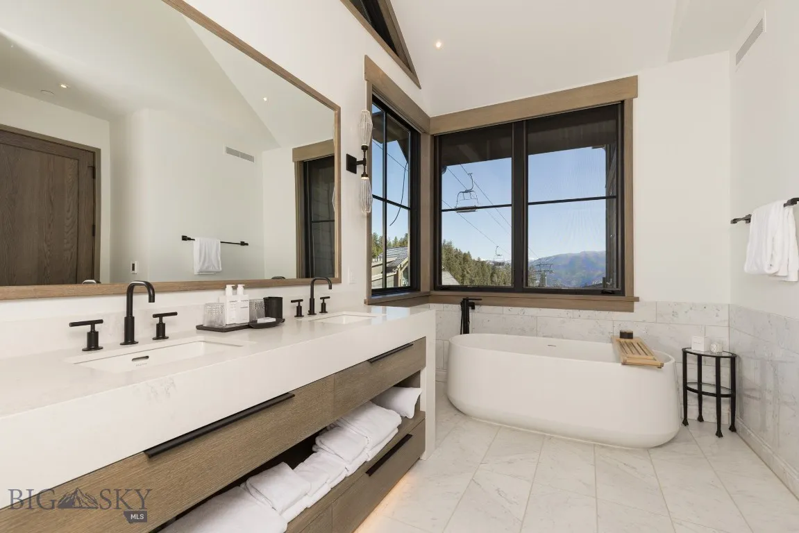 Bathroom with vanity, tile walls, a bath, and vaulted ceiling