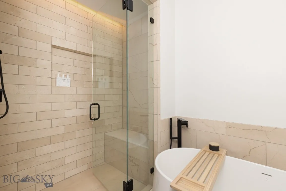 Bathroom featuring tile walls and shower with separate bathtub