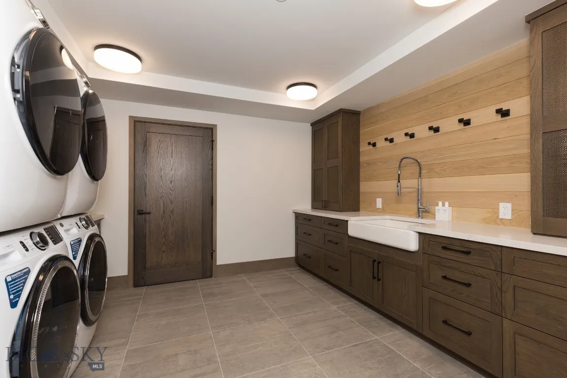Laundry area with sink, light tile patterned floors, and stacked washer / drying machine