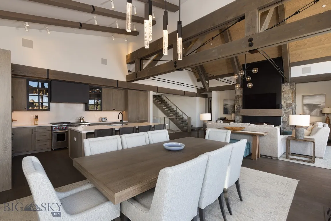 Dining area featuring high vaulted ceiling, track lighting, sink, beamed ceiling, and dark hardwood / wood-style flooring