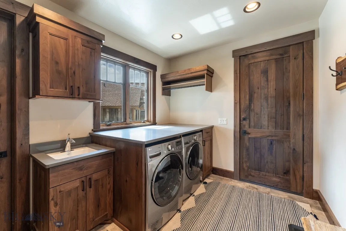 Clothes washing area with washing machine and clothes dryer, sink, and cabinets