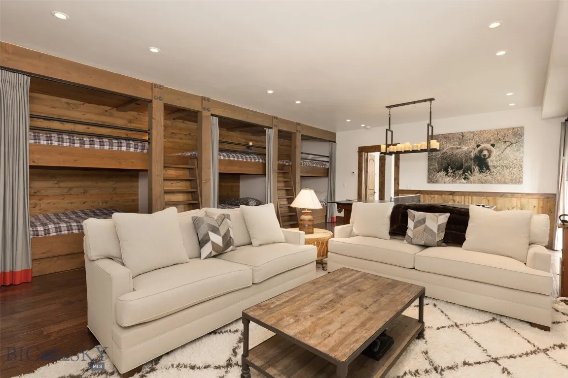 Versatile lower-level bunkroom and playroom featuring built-in sleeping quarters, a spacious lounge area, game table, wet bar, and direct patio access—perfect for entertaining guests or hosting family fun.