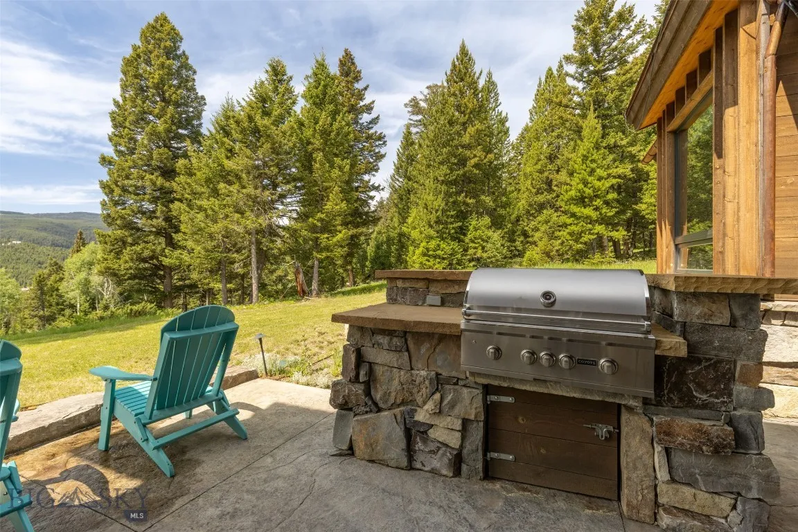 Expansive outdoor patio with ample seating, perfect for dining and relaxing while taking in unobstructed forest and mountain views.