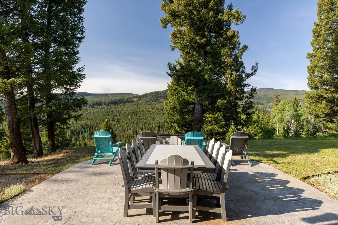 Expansive outdoor patio with ample seating, perfect for dining and relaxing while taking in unobstructed forest and mountain views.