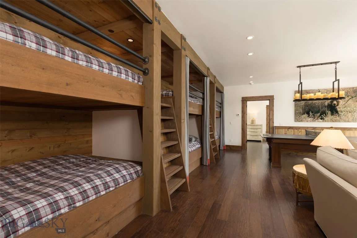 Versatile lower-level bunkroom and playroom featuring built-in sleeping quarters, a spacious lounge area, game table, wet bar, and direct patio access—perfect for entertaining guests or hosting family fun.