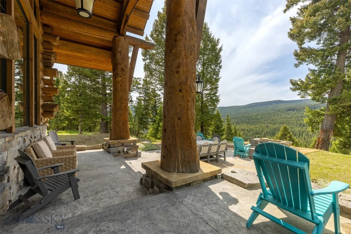 Expansive outdoor patio with ample seating, perfect for dining and relaxing while taking in unobstructed forest and mountain views.