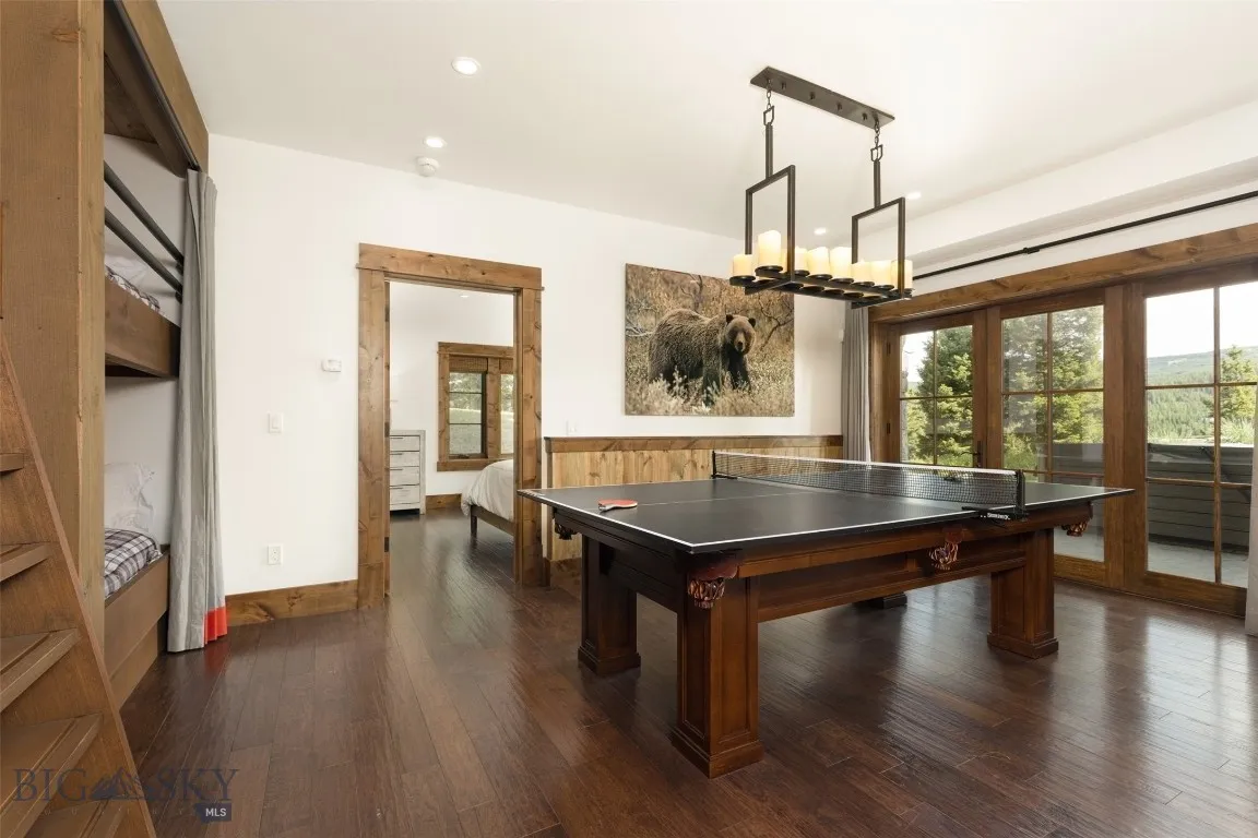 Versatile lower-level bunkroom and playroom featuring built-in sleeping quarters, a spacious lounge area, game table, wet bar, and direct patio access—perfect for entertaining guests or hosting family fun.