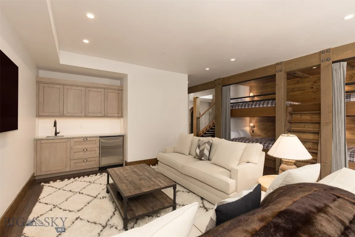 Versatile lower-level bunkroom and playroom featuring built-in sleeping quarters, a spacious lounge area, game table, wet bar, and direct patio access—perfect for entertaining guests or hosting family fun.