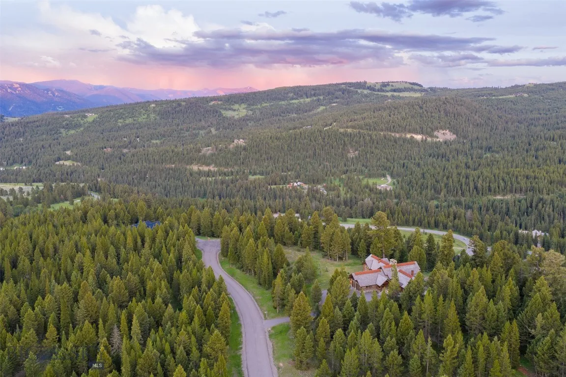 Aerial views showcase this exceptional mountain estate tucked into a private forested setting, with breathtaking scenery, winding roads, and stunning alpine surroundings—just minutes from world-class amenities.