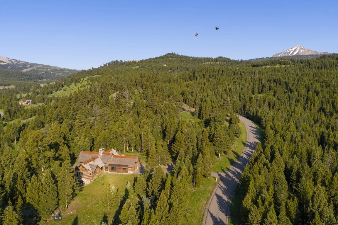 Aerial views showcase this exceptional mountain estate tucked into a private forested setting, with breathtaking scenery, winding roads, and stunning alpine surroundings—just minutes from world-class amenities.