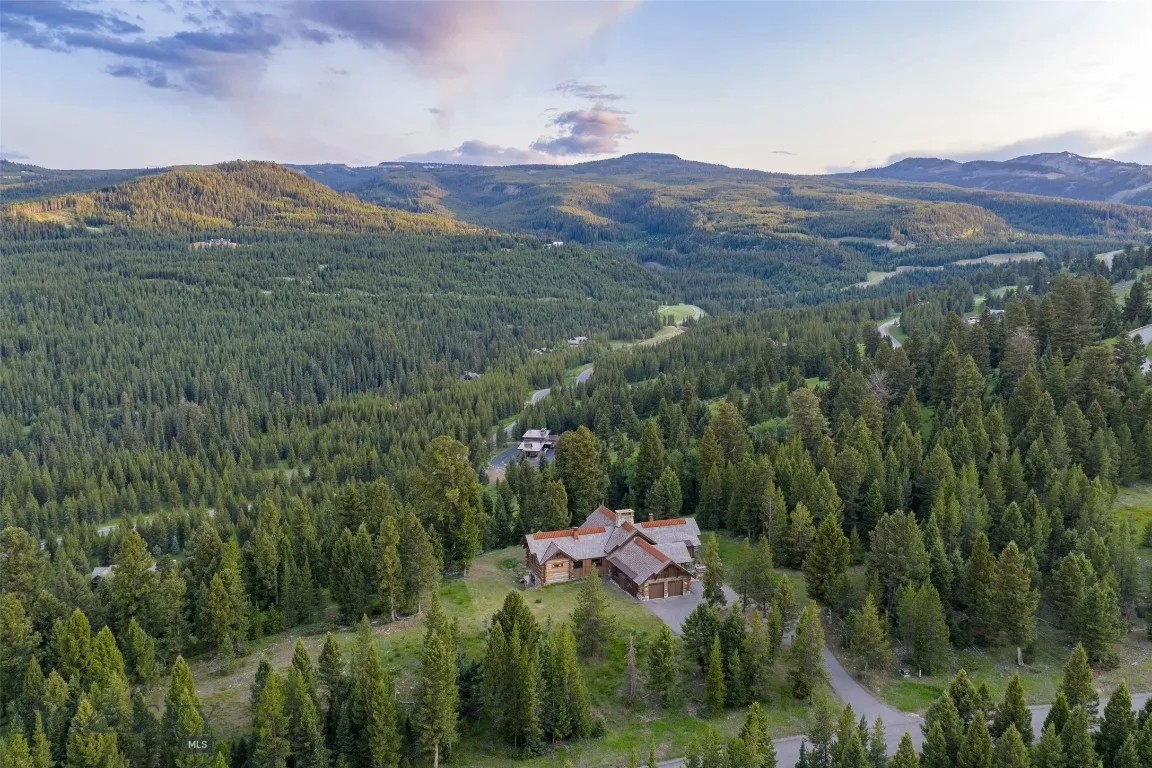 Aerial views showcase this exceptional mountain estate tucked into a private forested setting, with breathtaking scenery, winding roads, and stunning alpine surroundings—just minutes from world-class amenities.
