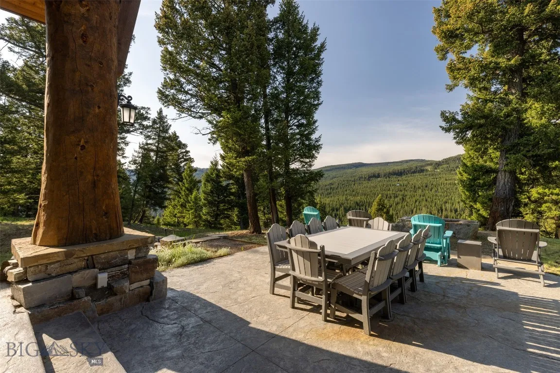 Expansive outdoor patio with ample seating, perfect for dining and relaxing while taking in unobstructed forest and mountain views.